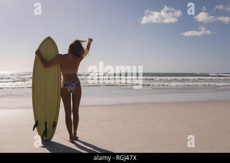 Femme debout avec surfeur surfboard on beach Banque D'Images