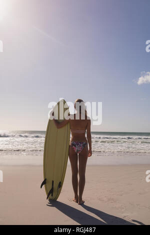 Femme debout avec surfeur surfboard at beach Banque D'Images