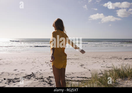 Jeune femme debout avec les bras tendus sur la plage