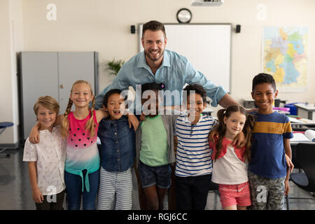 Heureux les enfants de l'école et l'enseignant et permanent à la caméra à l'école primaire en classe de Banque D'Images