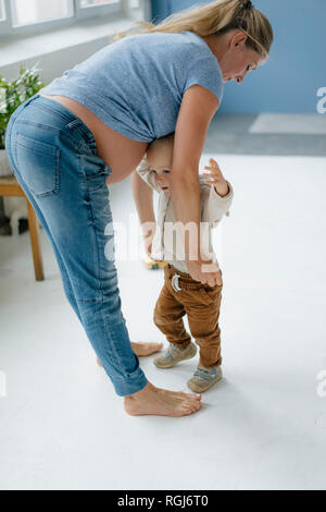 Mère enceinte avec petit garçon debout sur le plancher Banque D'Images