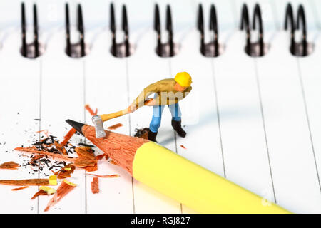 Diorama conceptuel image d'une figure miniature en affinant un crayon sur un carnet de notes Banque D'Images