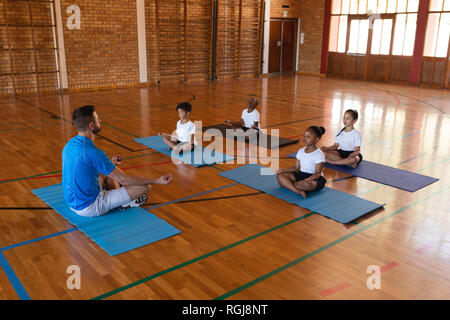 Vue latérale du professeur de yoga l'enseignement du yoga à l'école les enfants à l'école gymnast Banque D'Images