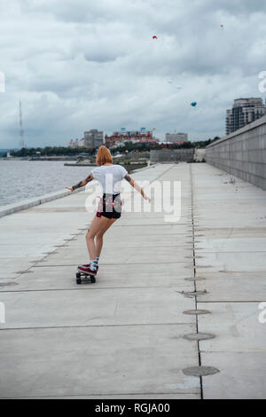 Vue arrière du jeune femme équitation carver skateboard du riverside Banque D'Images