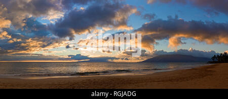 Vagues roulant sur une plage sous les nuages spectaculaires au coucher du soleil. Banque D'Images