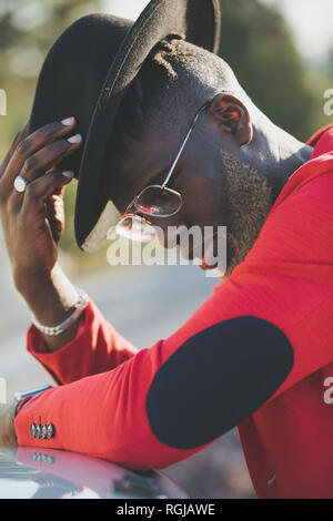 Noir à la mode homme portant chapeau et veste rouge Banque D'Images