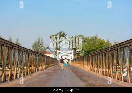 Deux jeunes garçons à pied sur une rivière qui traverse le pont de fer, Kampot, Cambodge. Banque D'Images