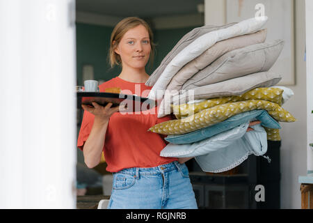 Portrait of young woman holding tray et coussins dans un café Banque D'Images