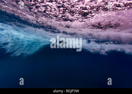 Maledives, vue sous l'eau de la vague, surfer assis sur une planche de surf, underwater Banque D'Images