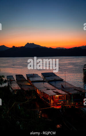 Incroyable coucher du soleil à Luang Prabang sur le Mékong. Maison du Tourisme et de bateaux dans l'eau. Ciel est en feu. Banque D'Images