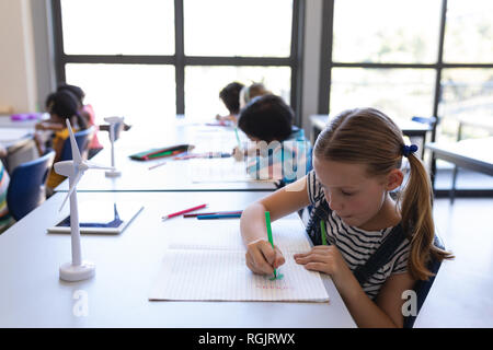 Vue latérale du dessin d'écolière sur livre à 24 en classe d'école primaire Banque D'Images