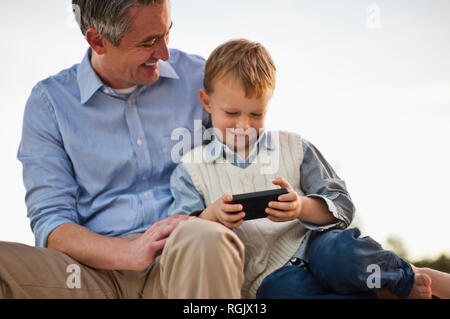 Curieusement Garçon jouant avec son père cellphone. Banque D'Images
