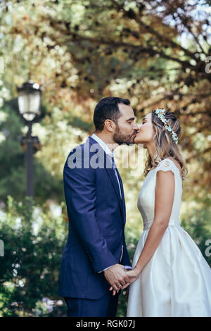 Happy young couple s'embrasser dans un parc, tout en se tenant la main Banque D'Images