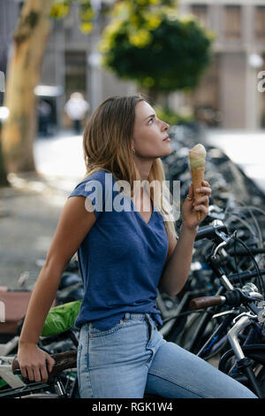 Pays-bas, Maastricht, blond young woman holding ice cream cone dans la ville au porte-vélo Banque D'Images