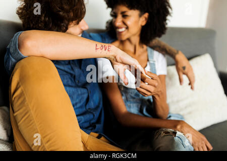 Heureux couple sitting on couch talking Banque D'Images
