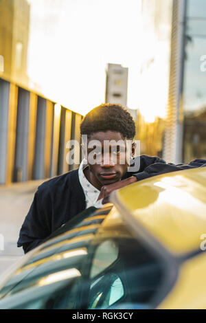 Portrait d'un jeune homme noir, debout près d'une voiture