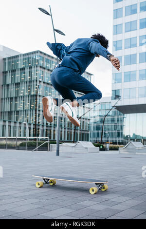 Espagne, Barcelone, jeune businessman doing skateboard tricks dans la ville Banque D'Images