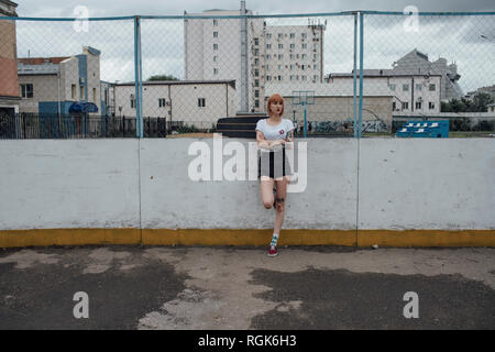 Jeune femme cool avec carver skateboard standing outdoors Banque D'Images