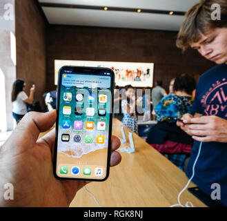 PARIS, FRANCE - Jul 16, 2018 : Apple Mac store moderne hall principal avec les clients et de l'homme main tenant la dernière version d'iPhone X avec écran OLED écran retina Banque D'Images