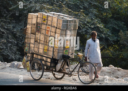 Tricycle surchargé d'homme avec les boîtes de conserve à Haridwar, Inde Banque D'Images