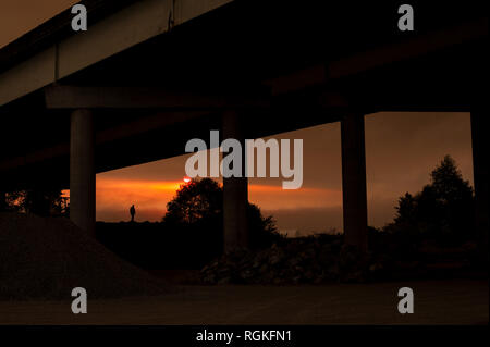 Silhouette d'homme sous freeway overpass at construction site Banque D'Images
