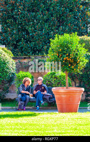 Vatican, Rome, Italie - 16 novembre 2018 : Deux touristes, l'homme et de la femme, couple, assis et au repos sur le banc près de l'arbre d'agrumes dans le jardin carré Banque D'Images