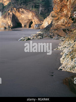 USA (Oregon), parc d'état de Hug Point, colorée et grès érodé cascade lointain. Banque D'Images