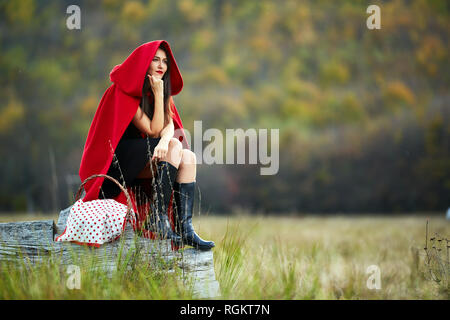 Femme vêtue comme Red Riding Hood dans diverses postures dans la forêt Banque D'Images