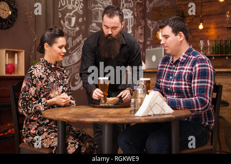 Hipster barman responsable de l'ordre de belle jeune couple.Grande Pub. Banque D'Images