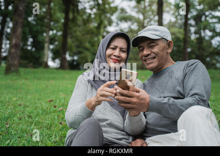 Les deux à l'aide d'ensemble dans le parc de smartphone Banque D'Images
