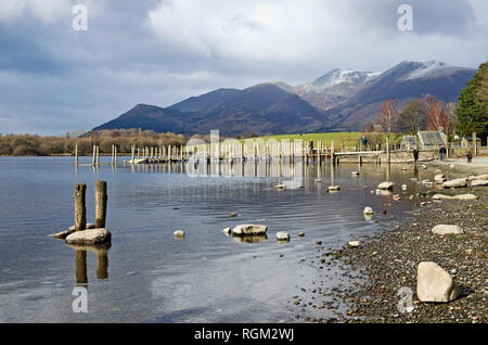 Visiteurs en rive du lac Derwentwater et sur les jetées en bois par old boat house, hiver, neige plafonnées Skiddaw derrière, Lake District, Cumbria, Angleterre Banque D'Images