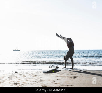 France, Bretagne, jeune homme faisant un ATR sur la plage à côté de surf Banque D'Images