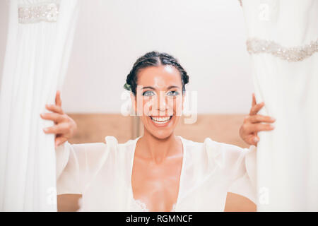 Portrait of happy woman opening curtain Banque D'Images