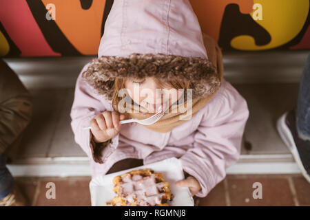 Belgique, little girl eating gaufre belge en hiver en plein air Banque D'Images