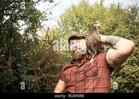 L'homme dans son propre jardin, l'homme avec free range chicken sur son épaule Banque D'Images