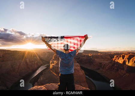 USA, Arizona, Colorado River, Horseshoe Bend, jeune homme sur viewpoint avec le drapeau américain Banque D'Images