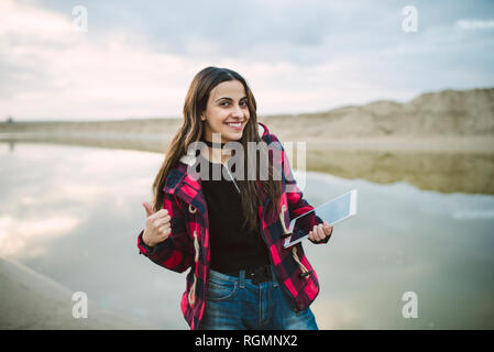 Portrait of smiling young woman with smartphone selfies sur la plage Banque D'Images