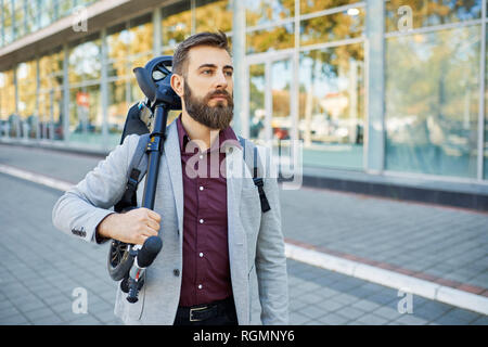 Businessman carrying scooter Banque D'Images