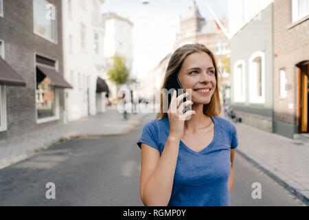 Pays-bas, Maastricht, smiling young woman on cell phone dans la ville Banque D'Images