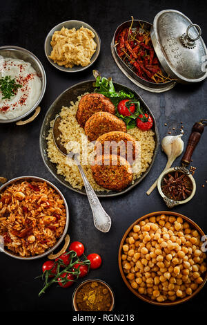 Juif au Moyen-Orient et un assortiment de plats préparés de la cuisine traditionnelle de levante dans les plats et casseroles vus du dessus servi sur la surface de la table sombre Banque D'Images