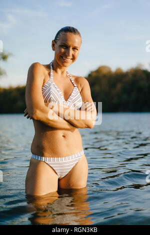 Portrait of smiling woman wearing a bikini dans un lac Banque D'Images