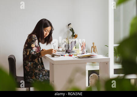 Illustrator assis à un bureau dans l'atelier dessin Banque D'Images