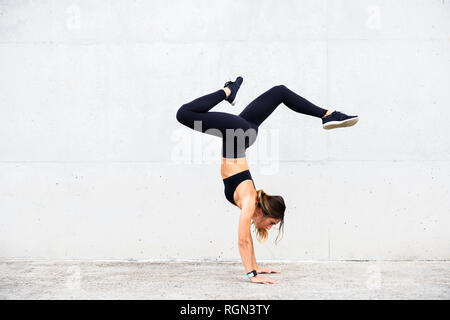 Athlète doing handstand in front of white wall Banque D'Images