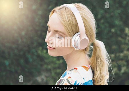 Jeune femme blanche a les yeux fermés et est proposé par l'écoute de la musique sur son casque Banque D'Images