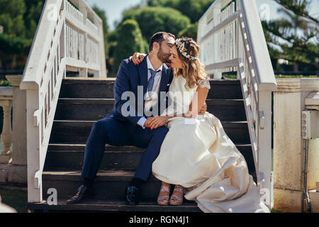 Young couple sitting on stairs profiter de leur jour de mariage Banque D'Images