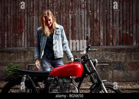 Smiling young woman standing next to motorcycle Banque D'Images