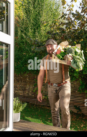 L'homme mature avec caisse de transport des légumes dans son jardin Banque D'Images