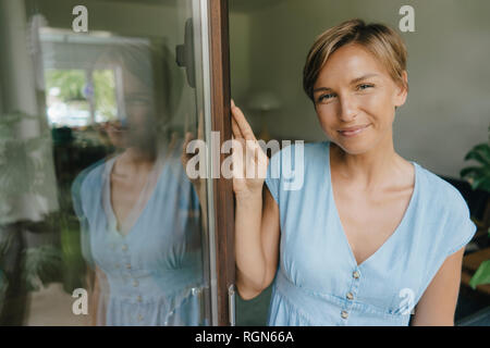 Portrait of smiling woman at porte-fenêtre Banque D'Images