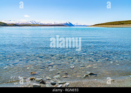 Nettoyer avec de l'eau claire peu profonde bas de galets autour du Lac Tekapo magnifique paysage et enneigés des Alpes du sud lointain Banque D'Images