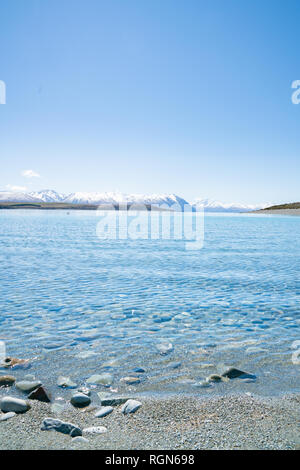 Nettoyer avec de l'eau claire peu profonde bas de galets autour du Lac Tekapo magnifique paysage et enneigés des Alpes du sud lointain Banque D'Images